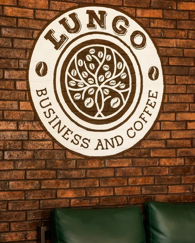 Logo de Lungo Business and Coffee sobre muro de ladrillo